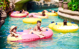Families enjoying a lazy river ride in colorful inflatable tubes.