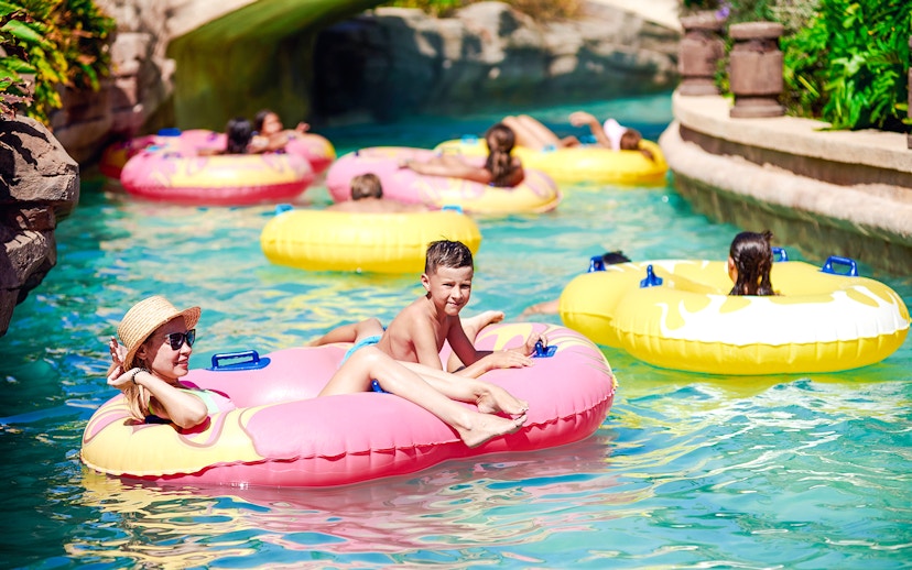 Families enjoying a lazy river ride in colorful inflatable tubes.