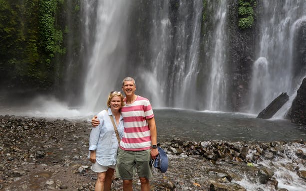 Couple standing in front of Sendang Gile waterfall in Lombok, Indonesia.