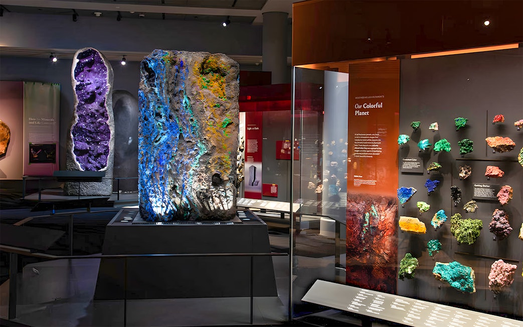 Colorful mineral exhibit at a museum, featuring large geodes and vibrant rock samples.