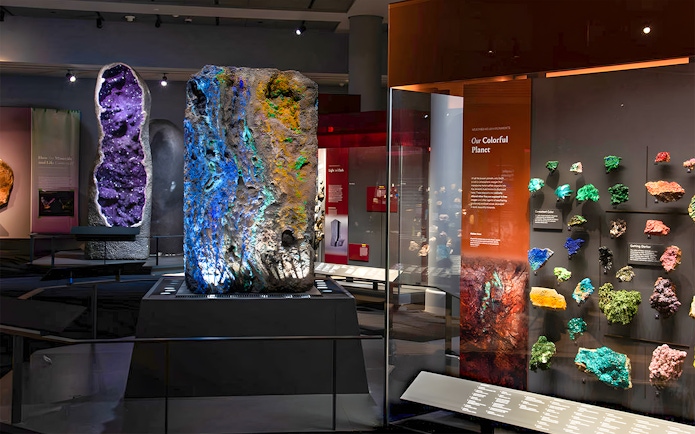 Colorful mineral exhibit at a museum, featuring large geodes and vibrant rock samples.