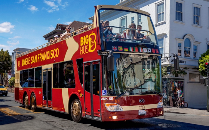 Open-top Big Bus tour in San Francisco passing through a city street.