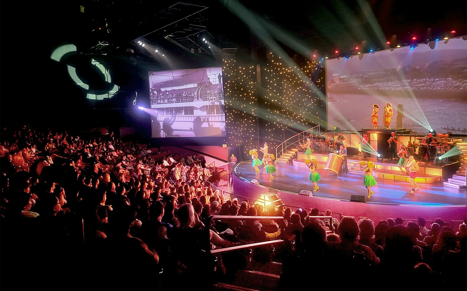 Audience watching performers on stage at the Rock-A-Hula Show in a pavilion.