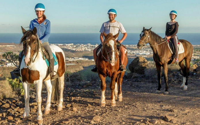 Horse riders on volcanic trail with ocean view in Gran Canaria.