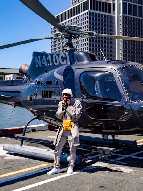 Helicopter parked at New York City pier with people nearby.