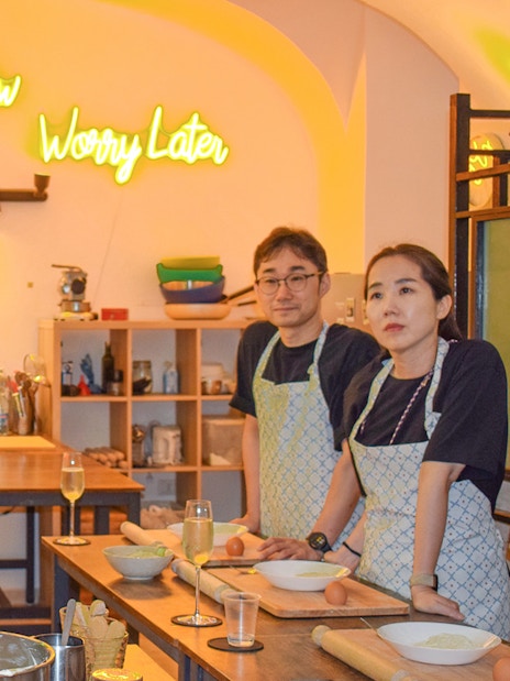 Instructor demonstrating tiramisu preparation in a cooking class with participants observing.