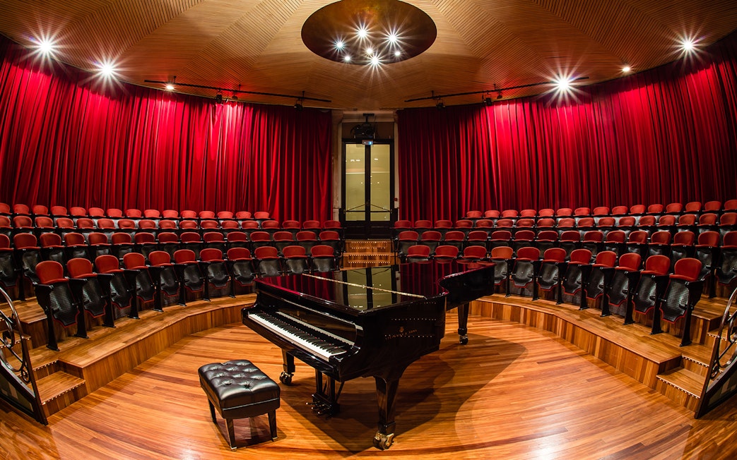 Grand piano on stage at Palau de la Música Catalana, Barcelona, with red seats and curtains.