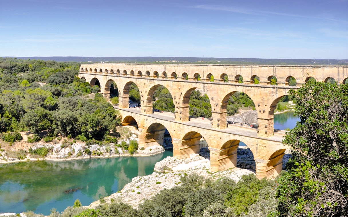Pont du Gard aqueduct spanning a river in a lush landscape, France.