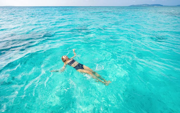 Snorkeler floating in clear turquoise waters of Ishigaki Island, Japan.