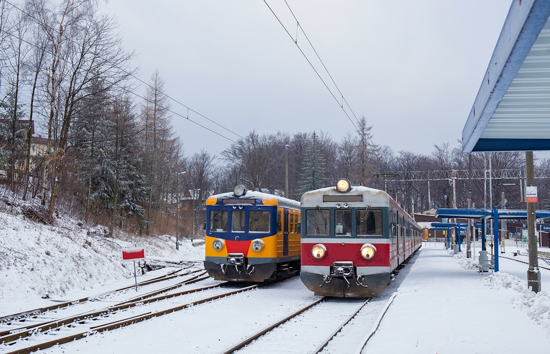 Two trains at a snowy Zakopane railway station in winter.