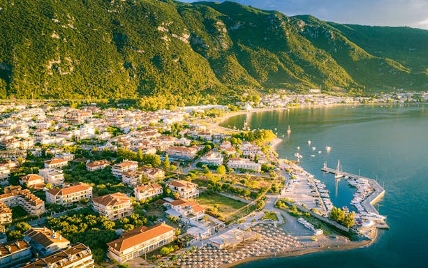 Aerial view of Kamena Vourla coastline with marina and lush mountains.