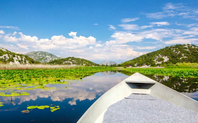 Boat ride on River of Crnojević, Lake Skadar National Park, surrounded by lush hills.