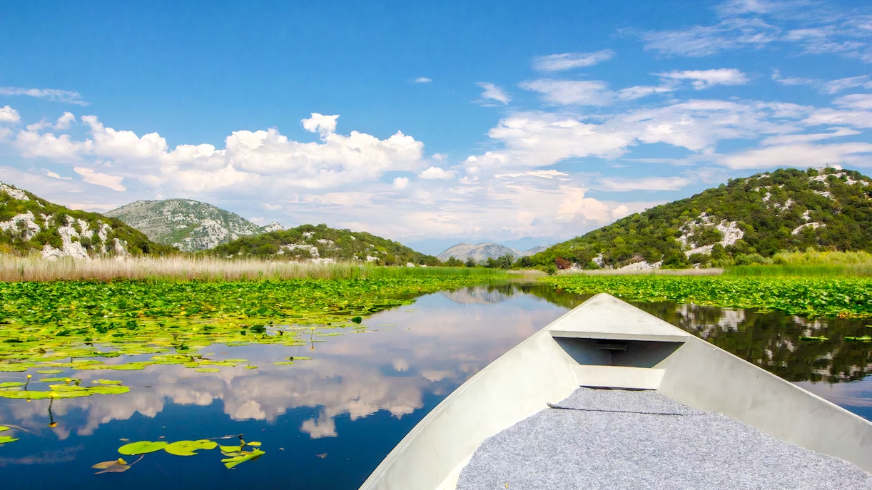 Boat ride on River of Crnojević, Lake Skadar National Park, surrounded by lush hills.