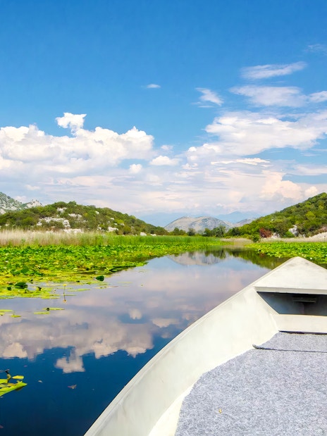 Boat ride on River of Crnojević, Lake Skadar National Park, surrounded by lush hills.