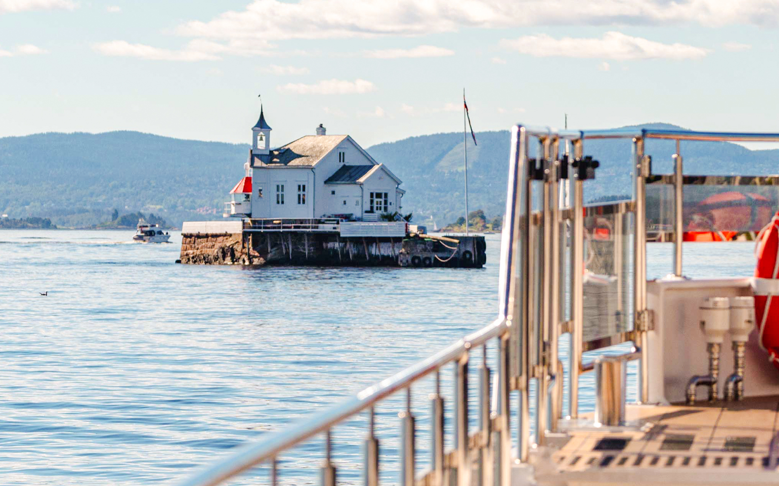Silent fjord cruise near Oslo with a view of a small island building and distant hills.