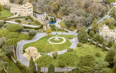 Aerial view of Vatican Gardens in Rome with pathways and a central statue.