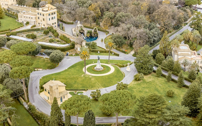 Aerial view of Vatican Gardens in Rome with pathways and a central statue.