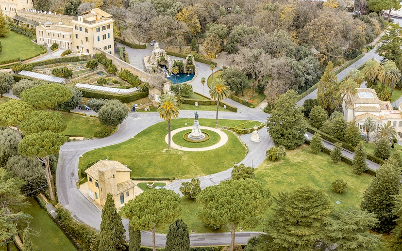 Aerial view of Vatican Gardens in Rome with pathways and a central statue.