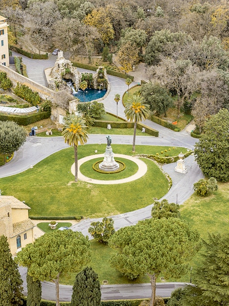 Aerial view of Vatican Gardens in Rome with pathways and a central statue.
