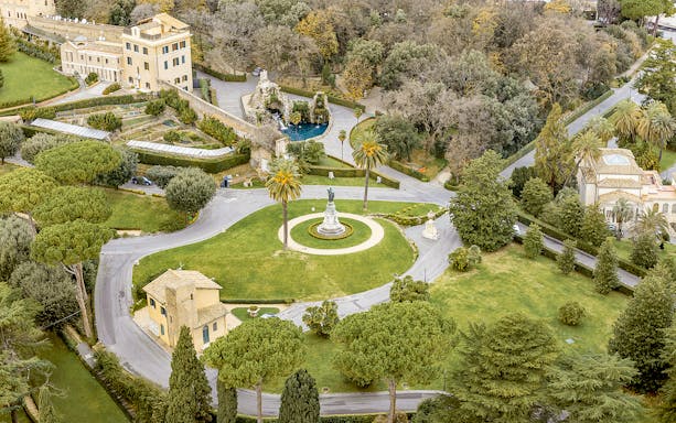 Aerial view of Vatican Gardens in Rome with pathways and a central statue.