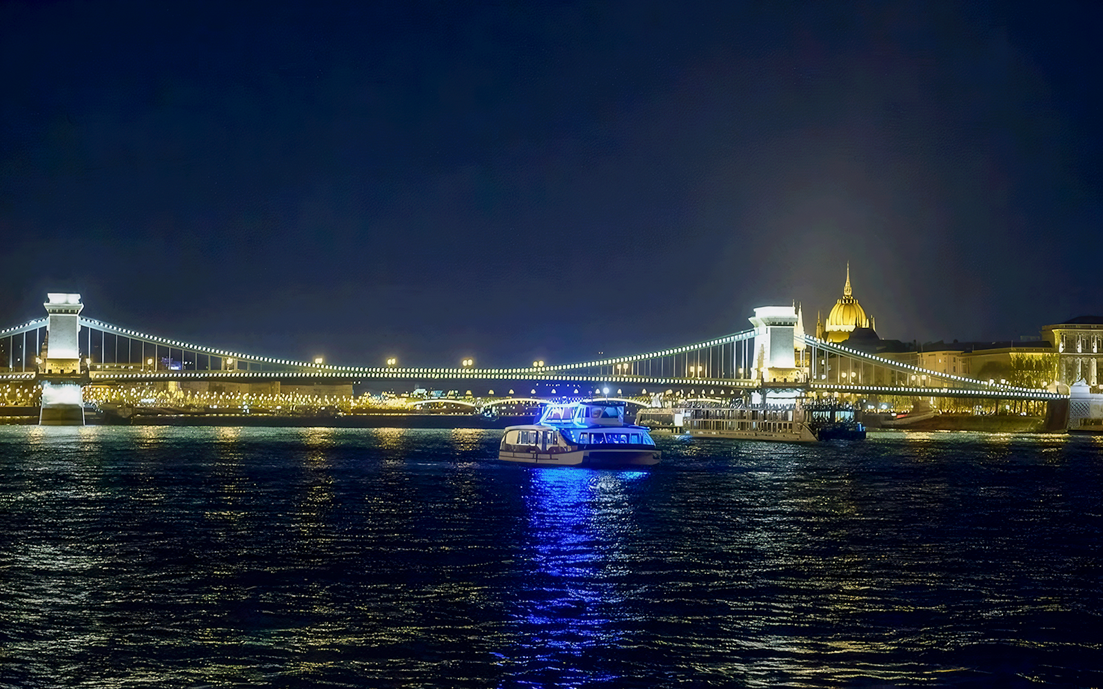 Christmas cruise on the Danube River with Budapest's Chain Bridge illuminated at night.