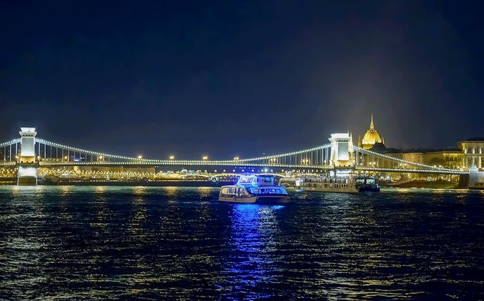 Christmas cruise on the Danube River with Budapest's Chain Bridge illuminated at night.