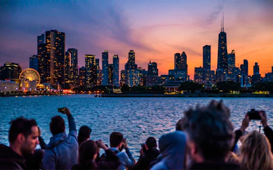 Chicago skyline at sunset viewed from a river cruise, with people taking photos.