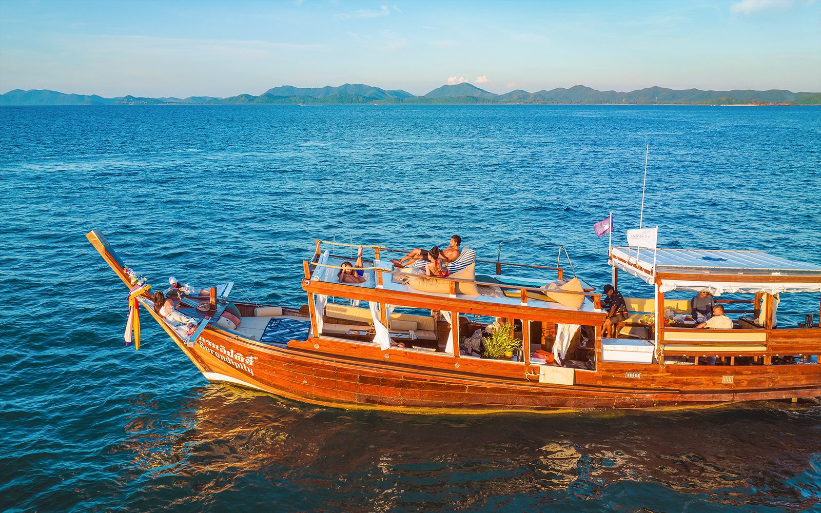 Luxury longtail boat cruise at sunset in Krabi with people relaxing on deck.