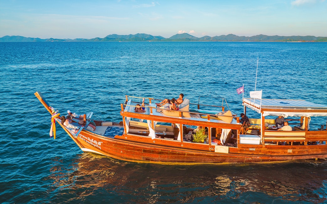 Luxury longtail boat cruise at sunset in Krabi with people relaxing on deck.
