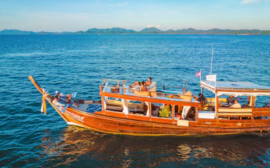 Luxury longtail boat cruise at sunset in Krabi with people relaxing on deck.