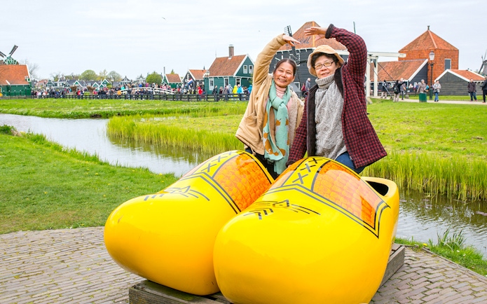 Guests posing in giant yellow clogs at Zaanse Schans, Netherlands.