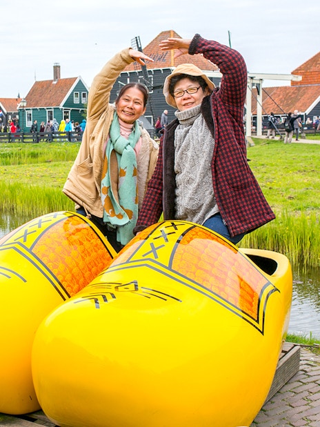 Guests posing in giant yellow clogs at Zaanse Schans, Netherlands.