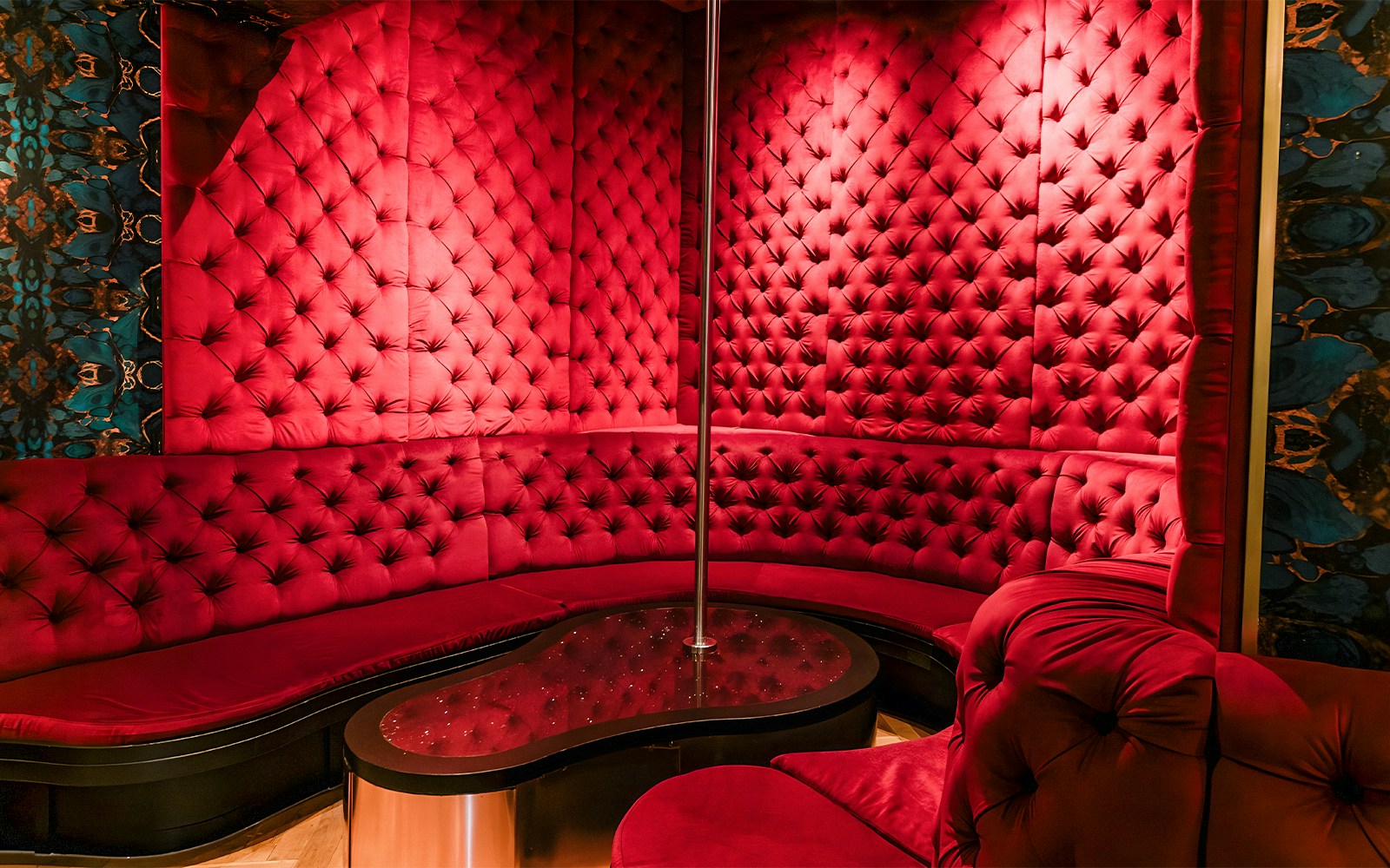 Luxurious red velvet seating area with a pole at Tour de BonTon strip club.