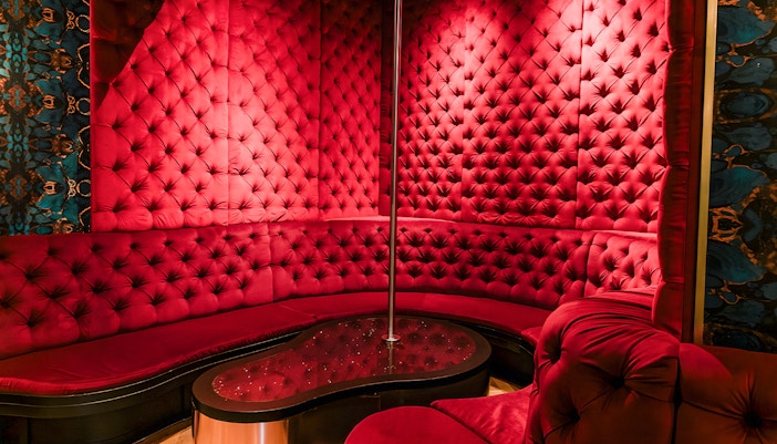 Tour de BonTon Amsterdam strip club interior with red velvet seating and stage.