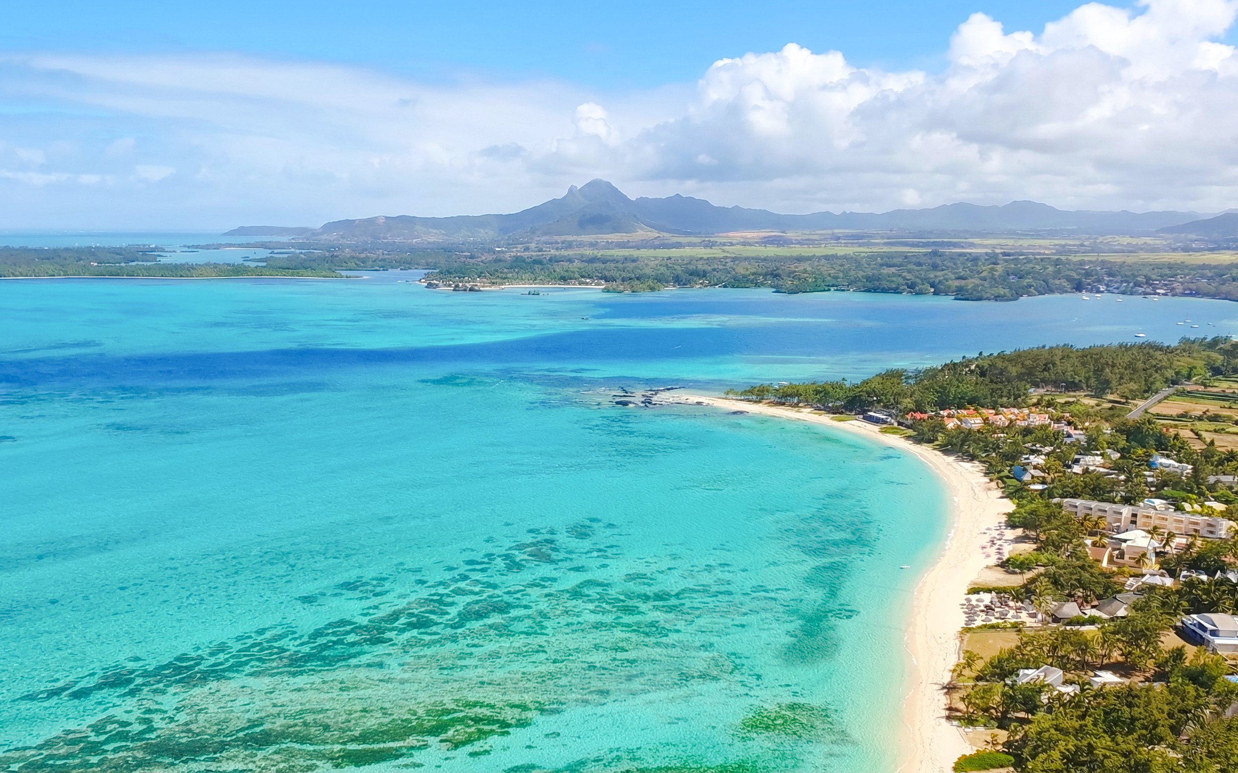 Aerial view of Mauritius coastline with turquoise waters and distant mountains on the Eastern Underwater Waterfall route.