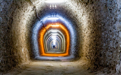 Underground tunnel at Salina Turda, Romania, with illuminated stone walls.
