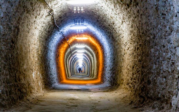 Underground tunnel at Salina Turda, Romania, with illuminated stone walls.