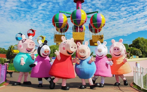 Peppa Pig characters at Paultons Park with colorful balloon ride in background.