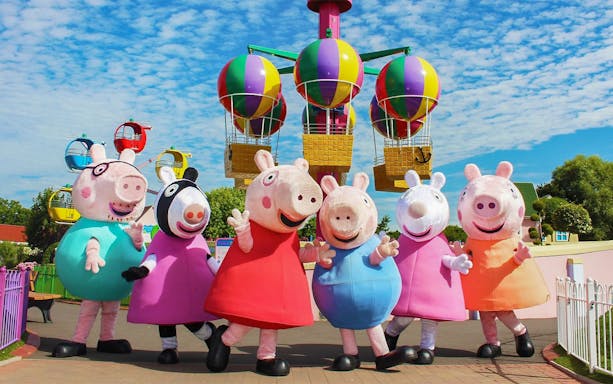 Peppa Pig characters at Paultons Park with colorful balloon ride in background.