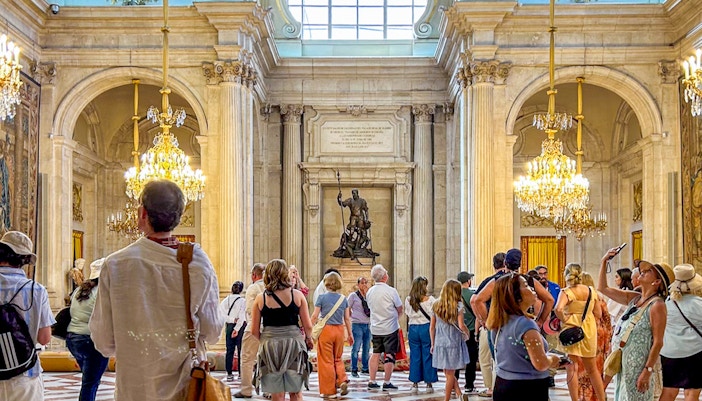 Royal Palace of Madrid grand hall with ornate chandeliers and intricate ceiling details.