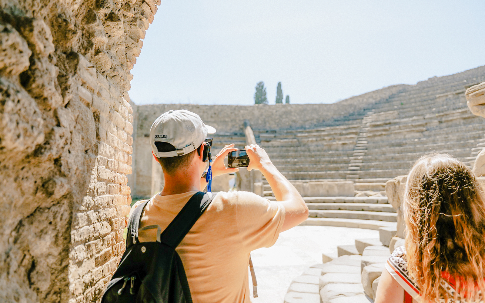Tourists photographing the ancient amphitheater in Pompeii.