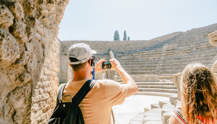 Tourists photographing the ancient amphitheater in Pompeii.