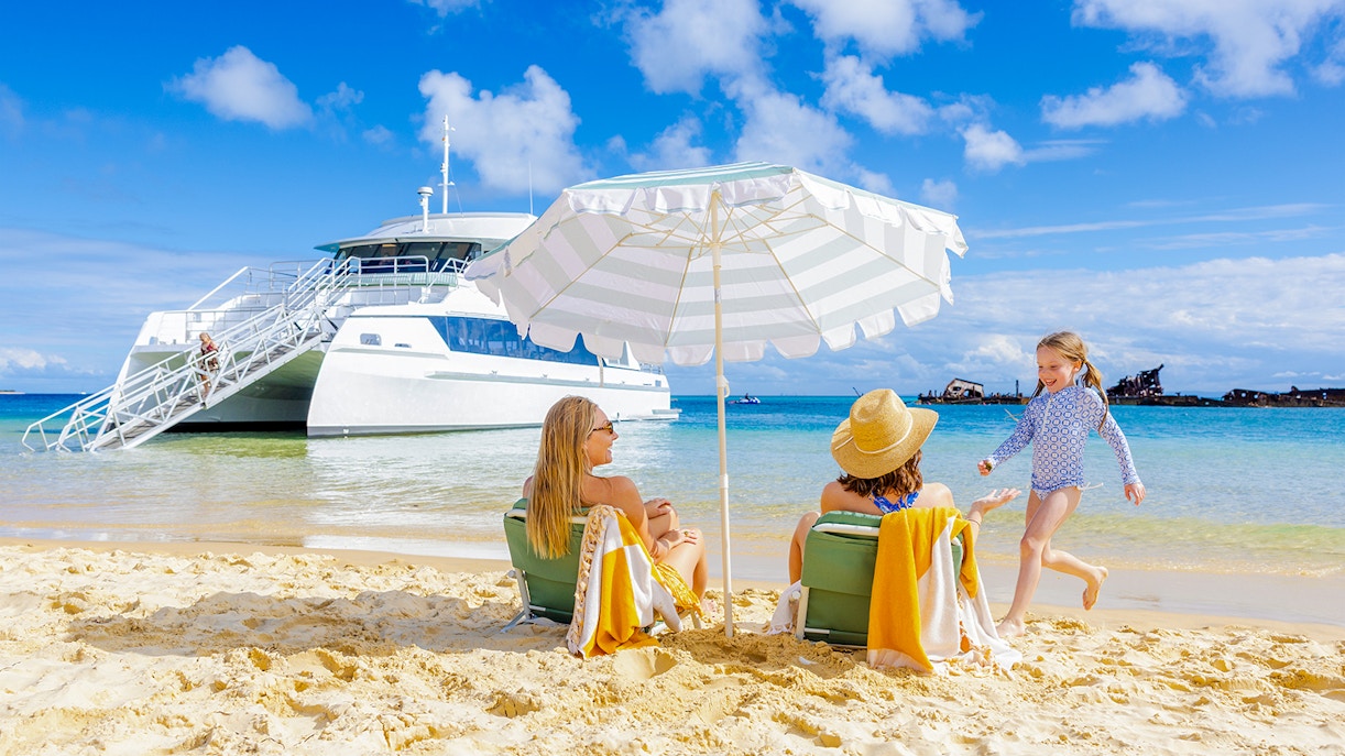 Family relaxing on Moreton Island beach with cruise ship in background, Australia.