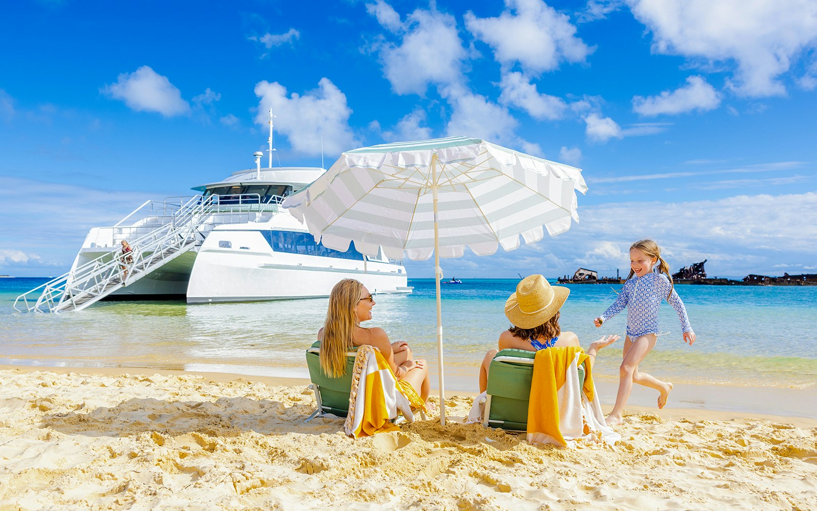Family relaxing on Moreton Island beach with cruise ship in background, Australia.