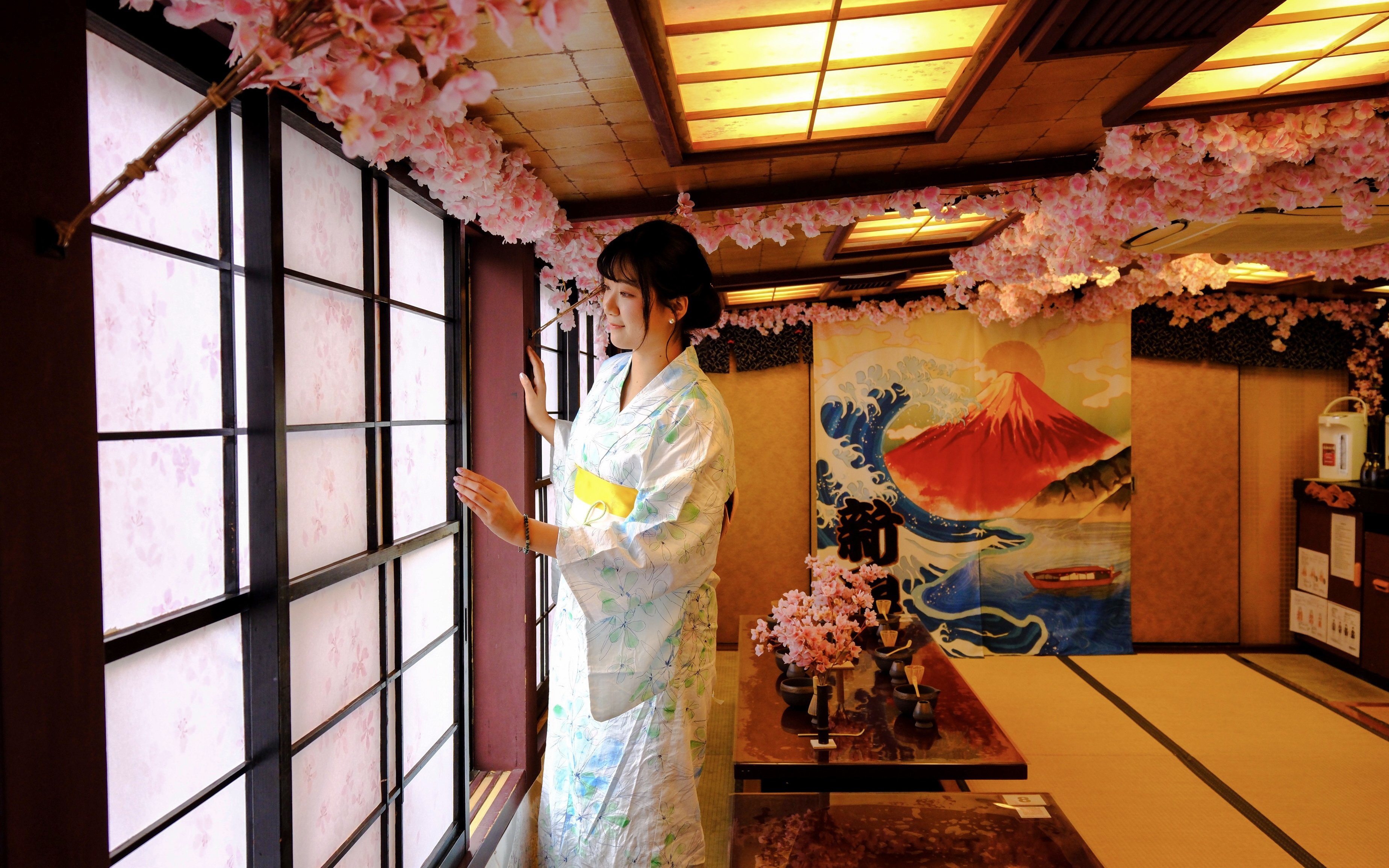 Woman in kimono at Tokyo tea ceremony room with cherry blossoms and Mount Fuji artwork.