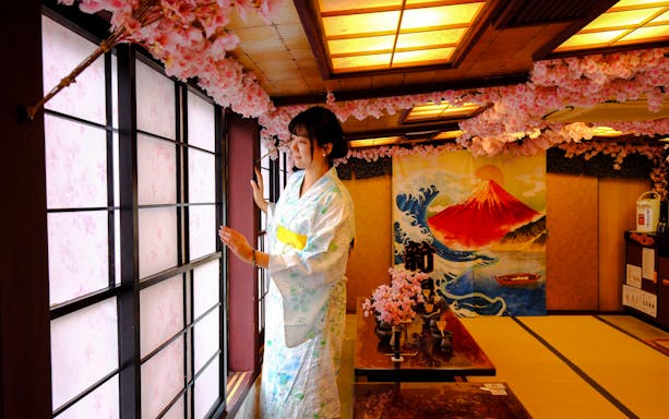 Woman in kimono at Tokyo tea ceremony room with cherry blossoms and Mount Fuji artwork.