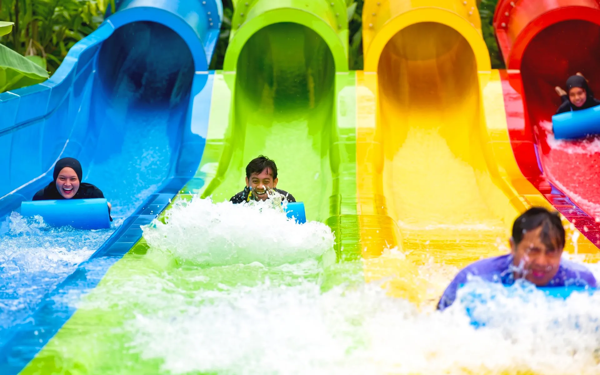 People sliding down colorful water slides at SplashMania Waterpark.