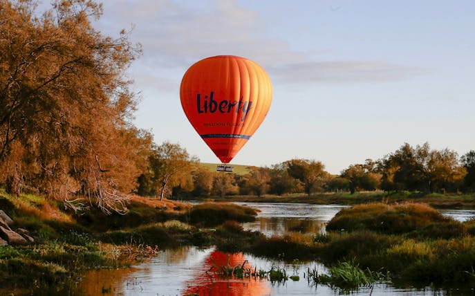 Hot air balloon over Avon Valley landscape with river and trees.
