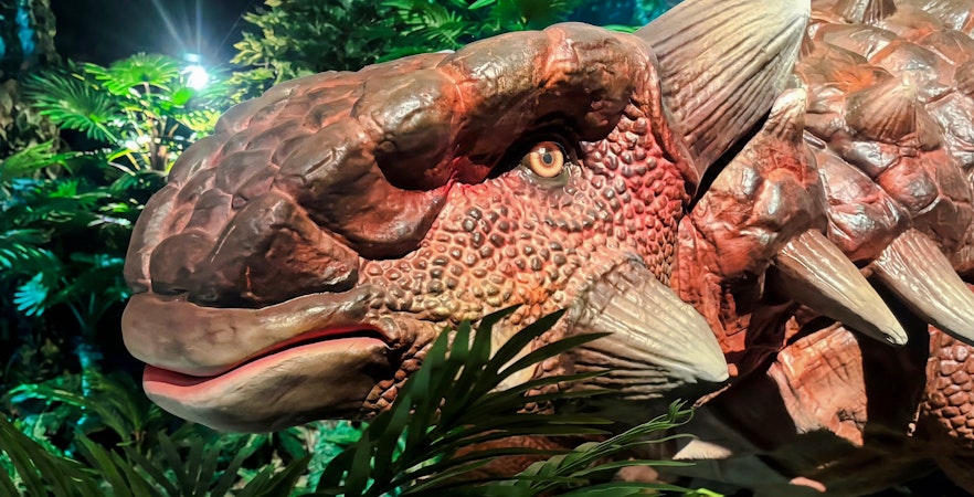 Dinosaur model in lush exhibit at Dinosaurs: The Immersive Odyssey VR Experience.