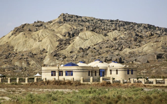 Museum building with domed roofs in Gobustan National Park, Azerbaijan, set against rocky hills.